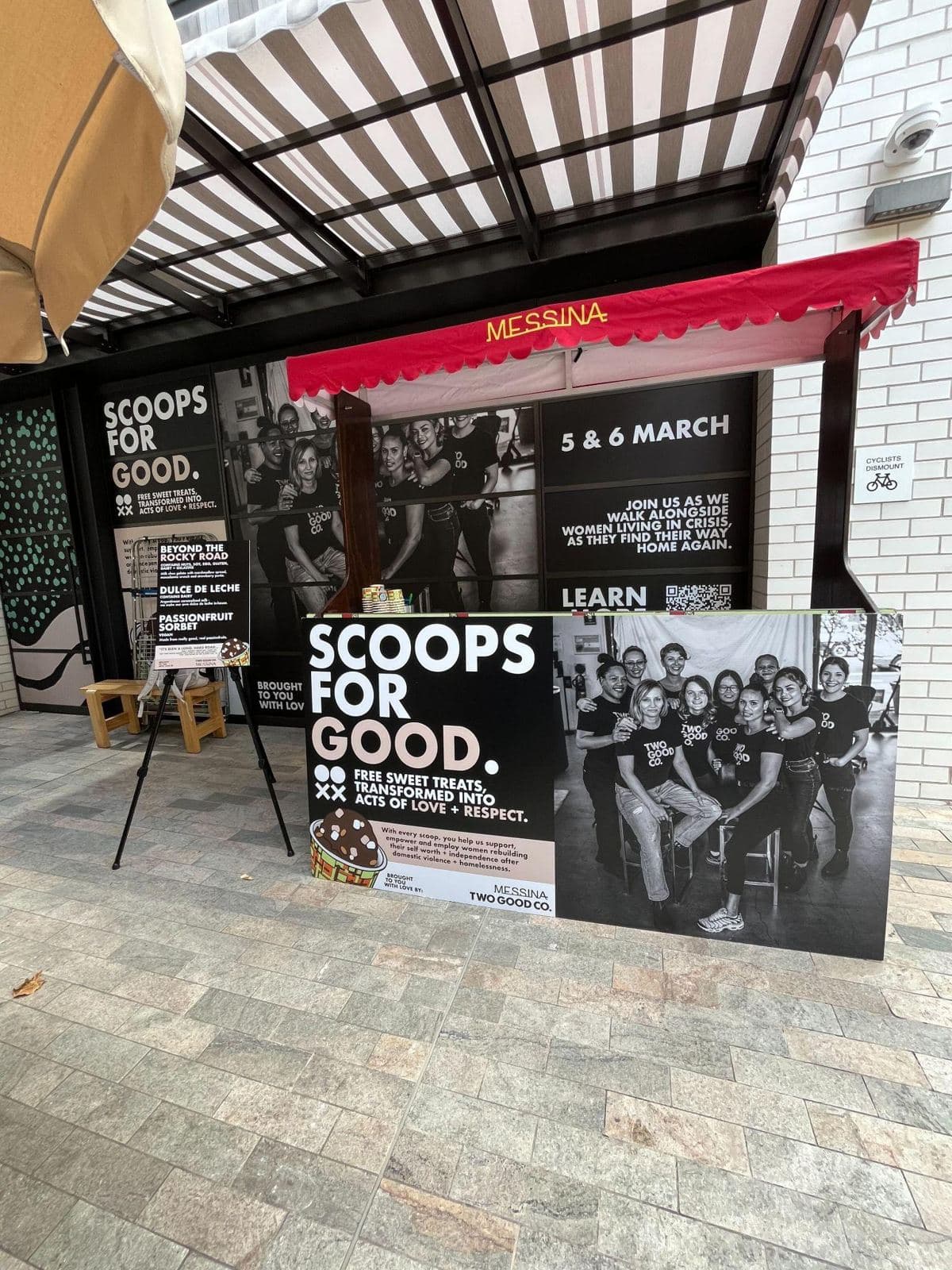 Large gelato stand with black and white Scoops for Good panels at a street event